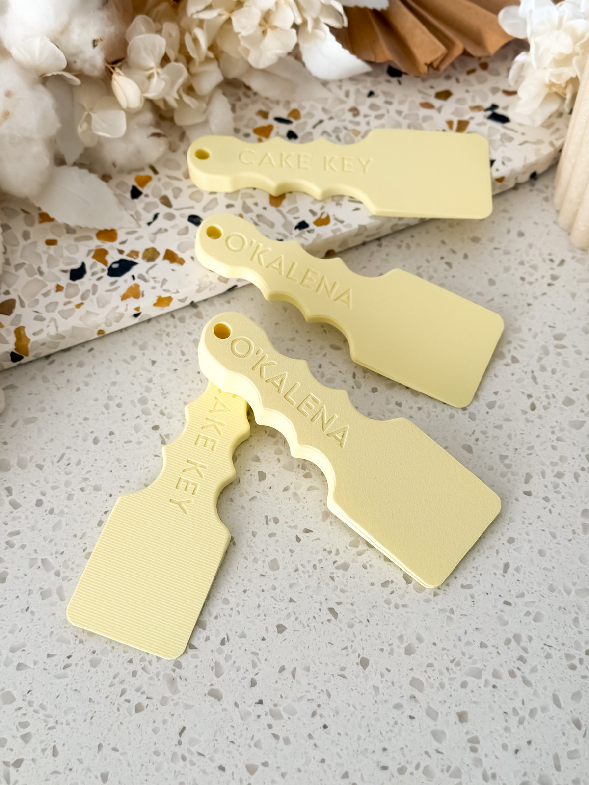 Three Cake Key™ magnetic cake board lifters by O'Khach on a terrazzo bench
