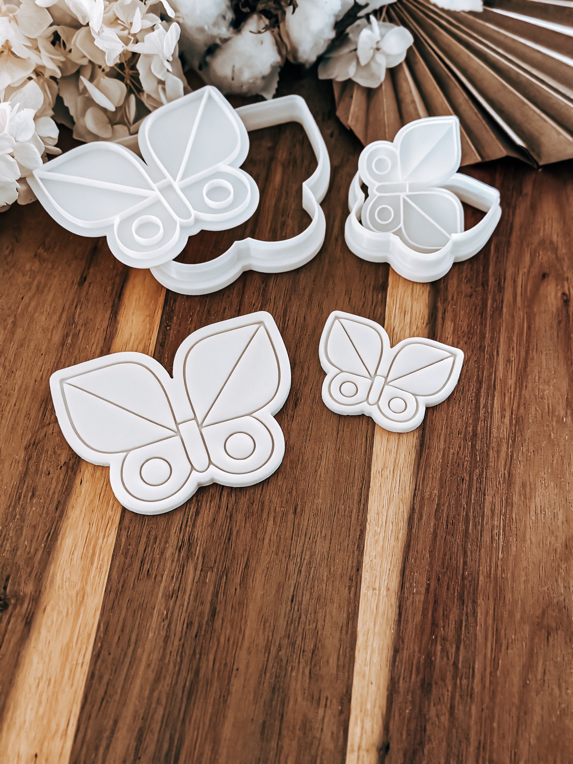 Butterfly-shaped cookie cutters on a wooden surface with flowers in the background