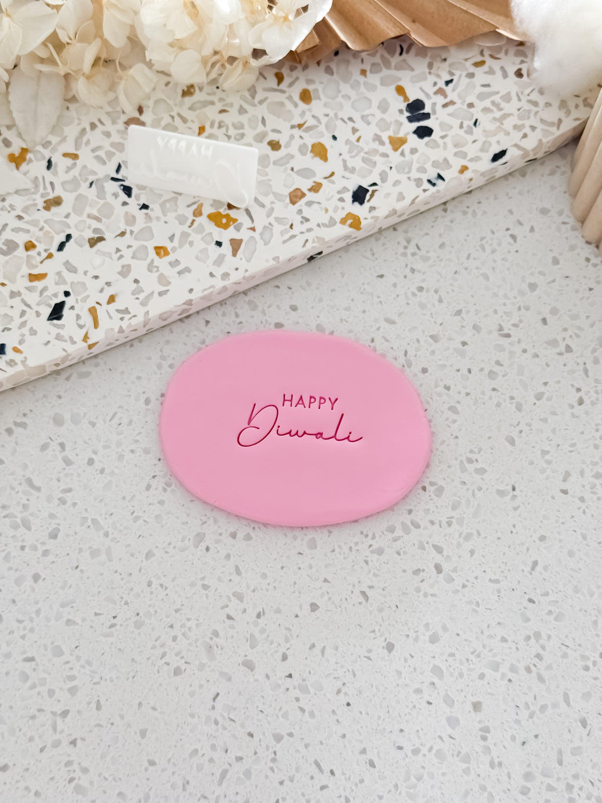 Happy Diwali cookie stamp by O'Khach, shown stamped in pink fondant